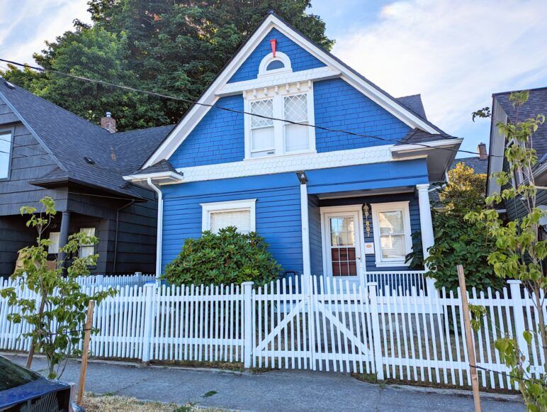 A small blue house with a white picket fence.