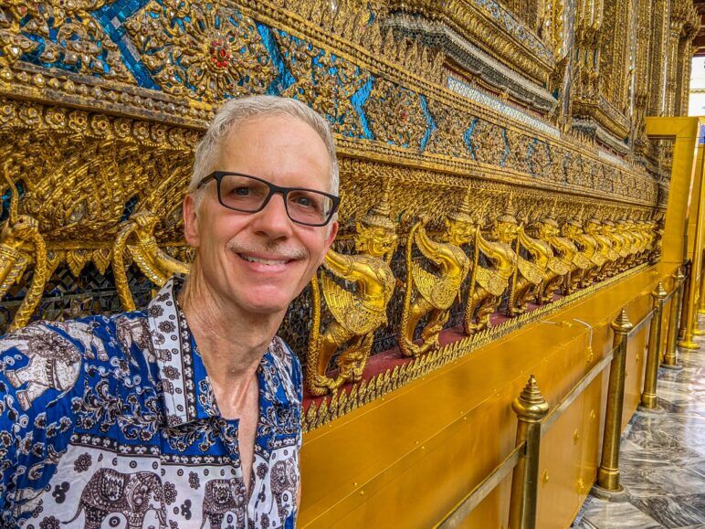 The author stands against a wall inside a Bangkok temple.