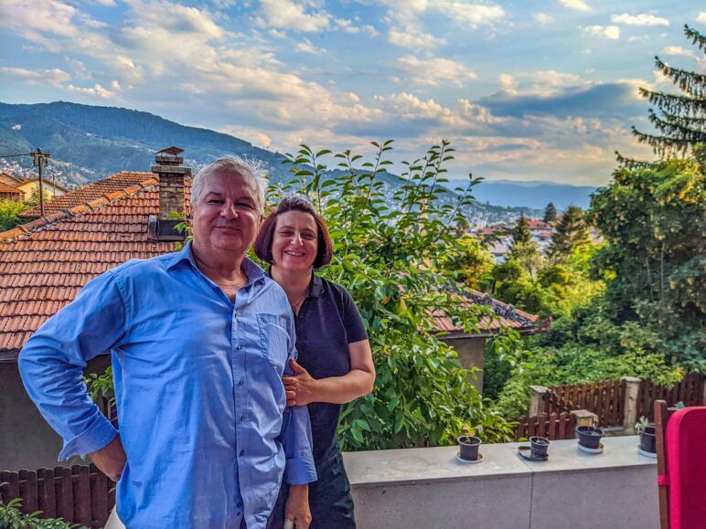 A man and woman pose in front of their home in Sarajevo.