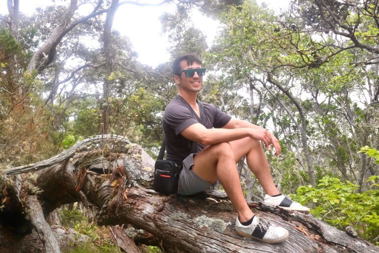 Author sitting on fallen tree during a volcano hike.