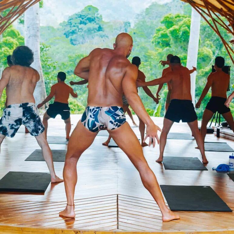 A group of men facing away from the camera do yoga