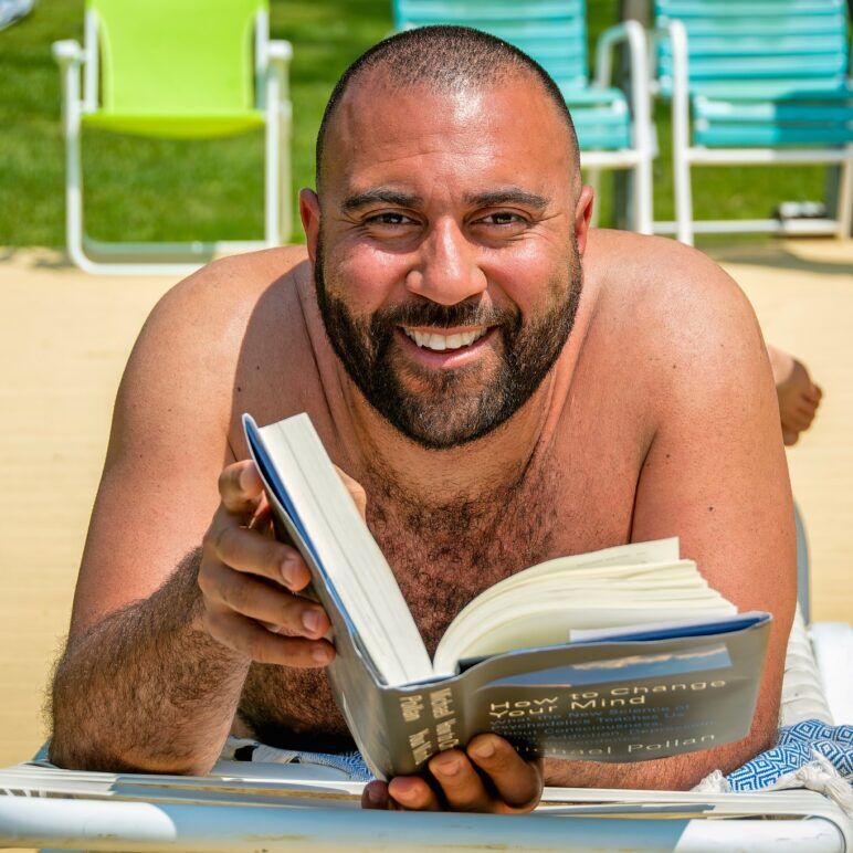 A man lays on the beach reading a book