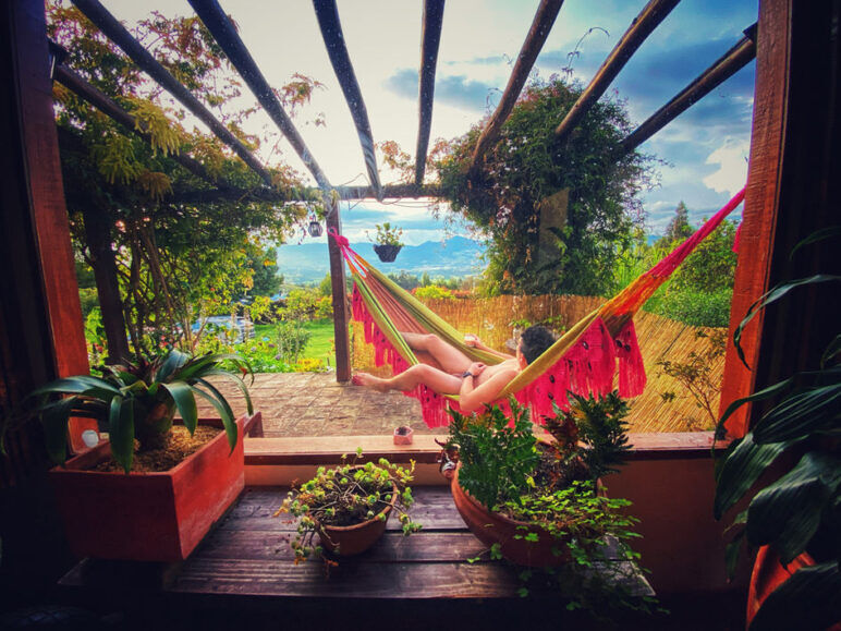 A man with no clothes lounges in a hammock