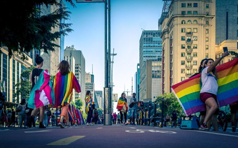 Different people carrying Pride flags down the street. 
