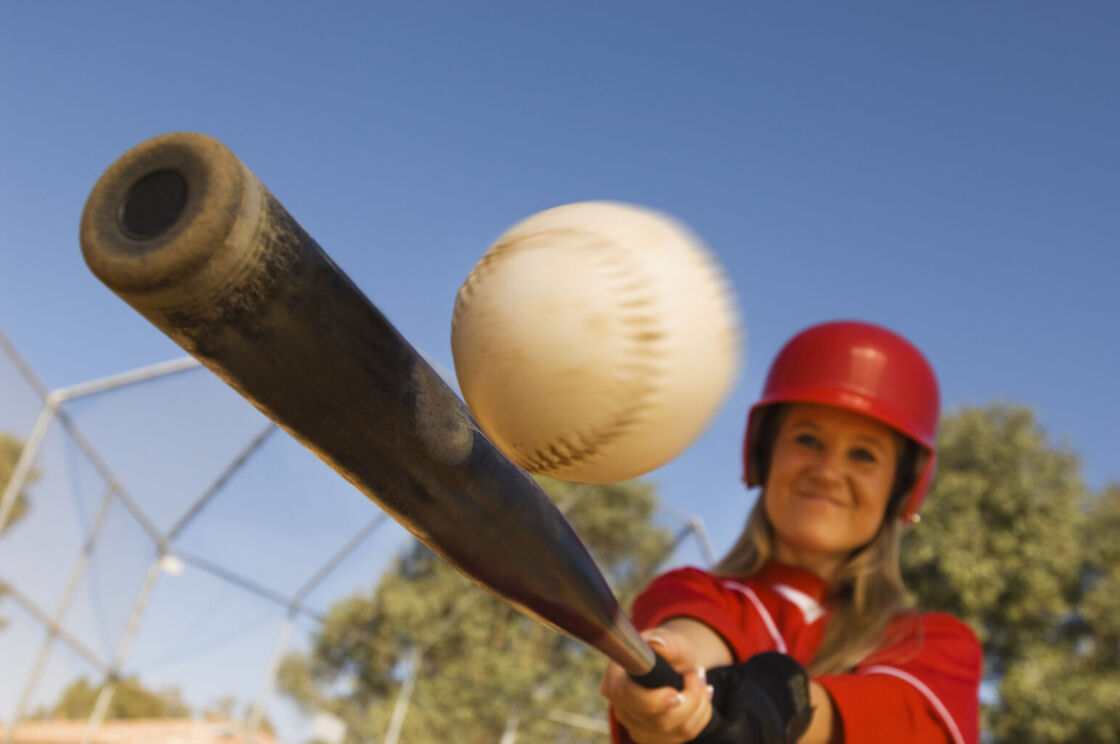 A female softball player about to hit the ball.