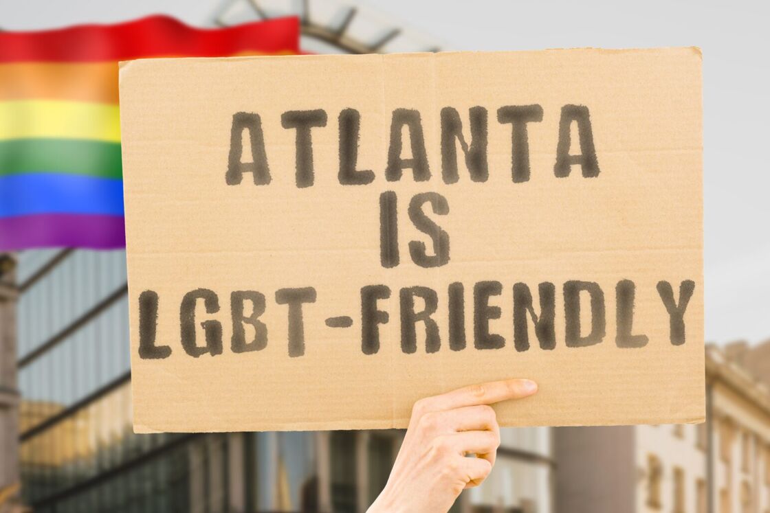 A cardboard sign in front of the Pride flag reading "Atlanta is LGBT-friendly."