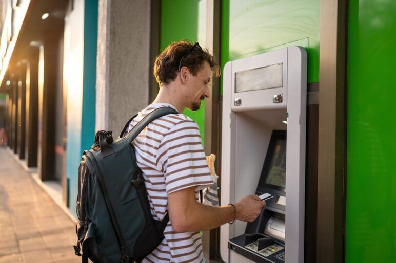 illennial tourist using atm machine to withdraw money