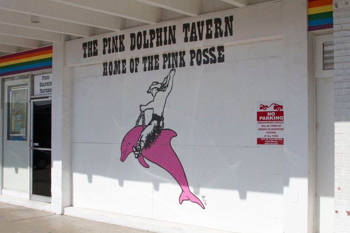 The wall of the Pink Dolphin Tavern with a text reading "Home of the Pink Posse" and a visual of woman with cowboy hat riding a pink dolphin.