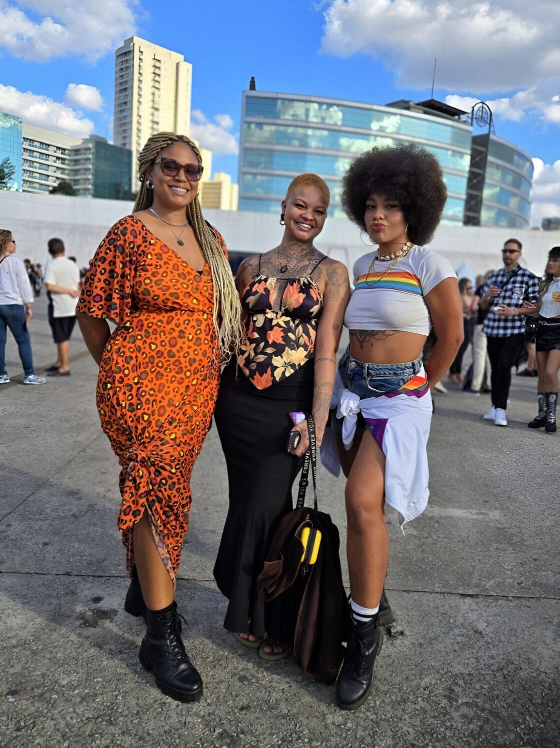 Three women pose smiling outdoors at São Paulo Pride.