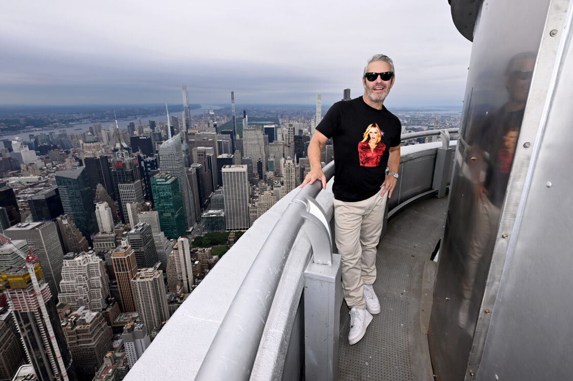 Andy Cohen poses in sunglasses on the balcony of the Empire State Building.