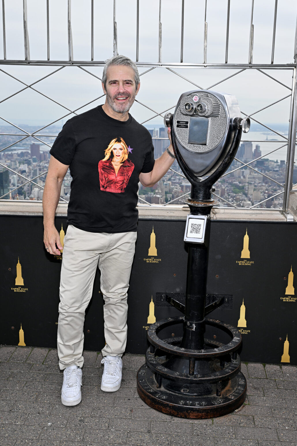 Andy Cohen poses with binoculars on the balcony of the Empire State Building.