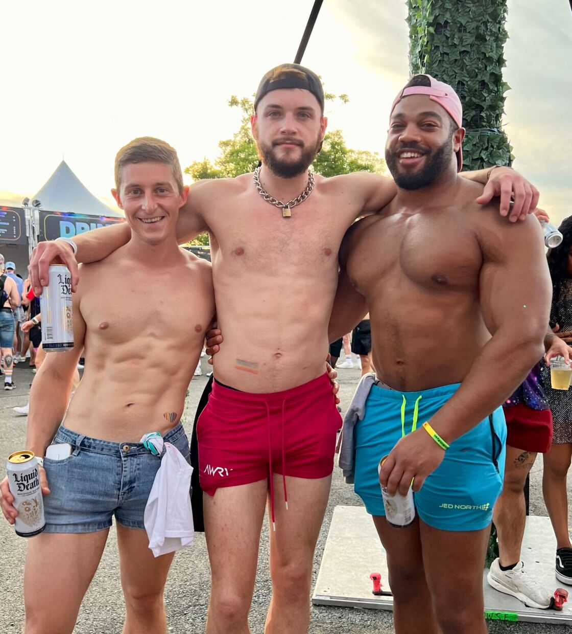 Three men with their shirts off pose for the camera