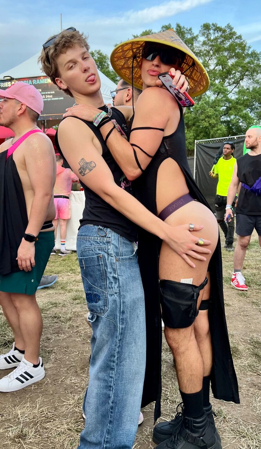 A person in a black tanktop and jeans embraces a woman wearing almost nothing