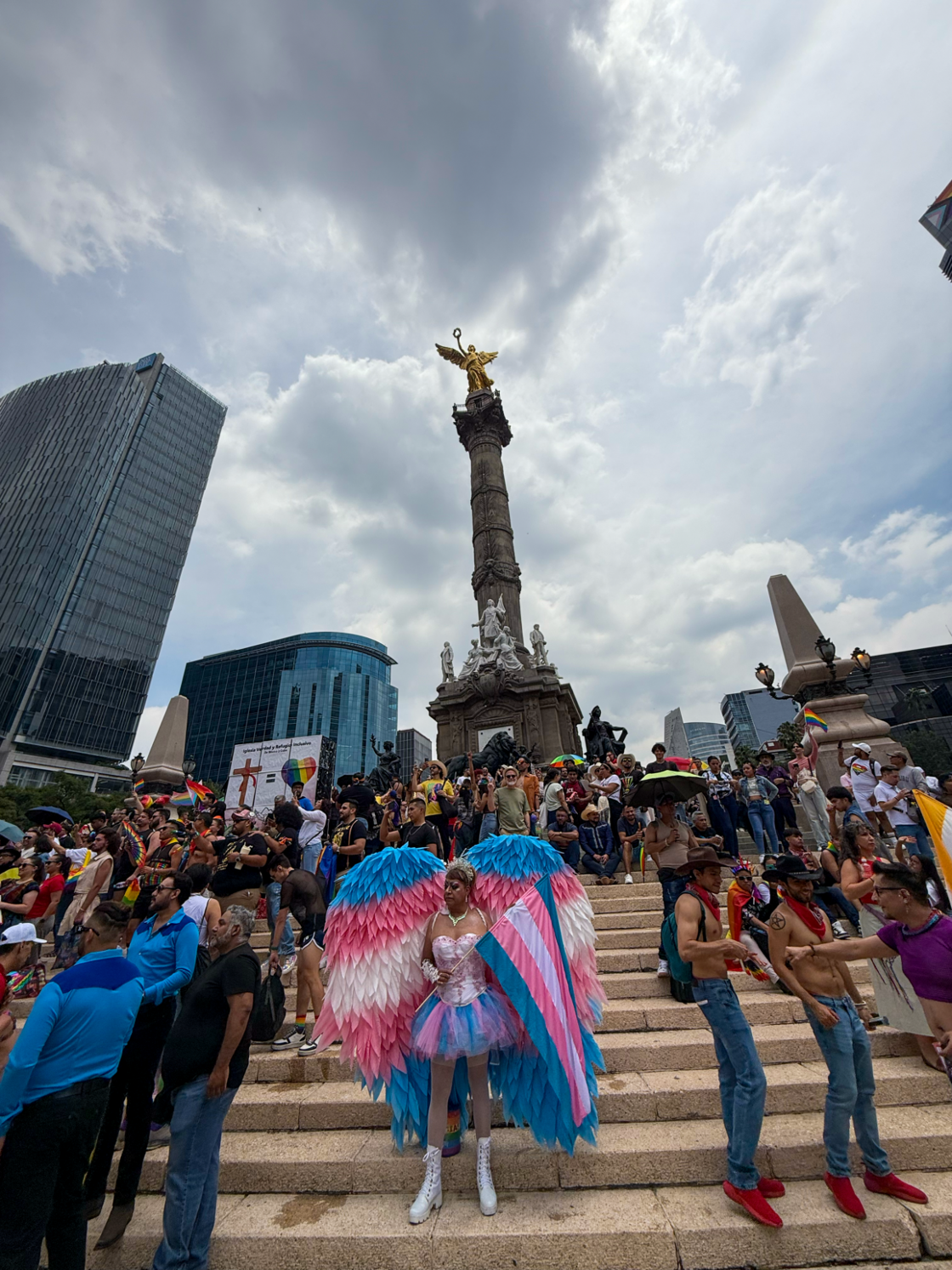 A group of Pride attendees stand around The Angel of Independence in Mexico City.