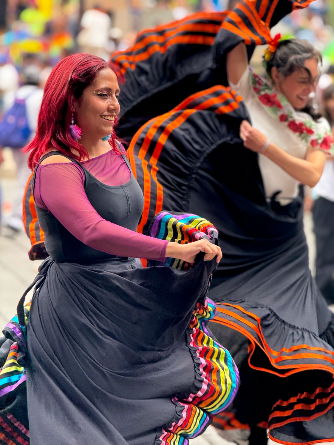 Two woman dance in long rainbow dresses at Mexico City Pride.