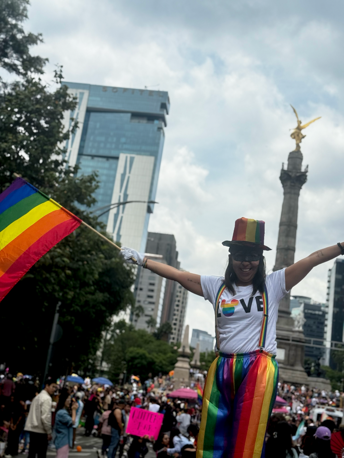 A woman poses in long rainbow pants and a rainbow hat at Mexico City Pride.