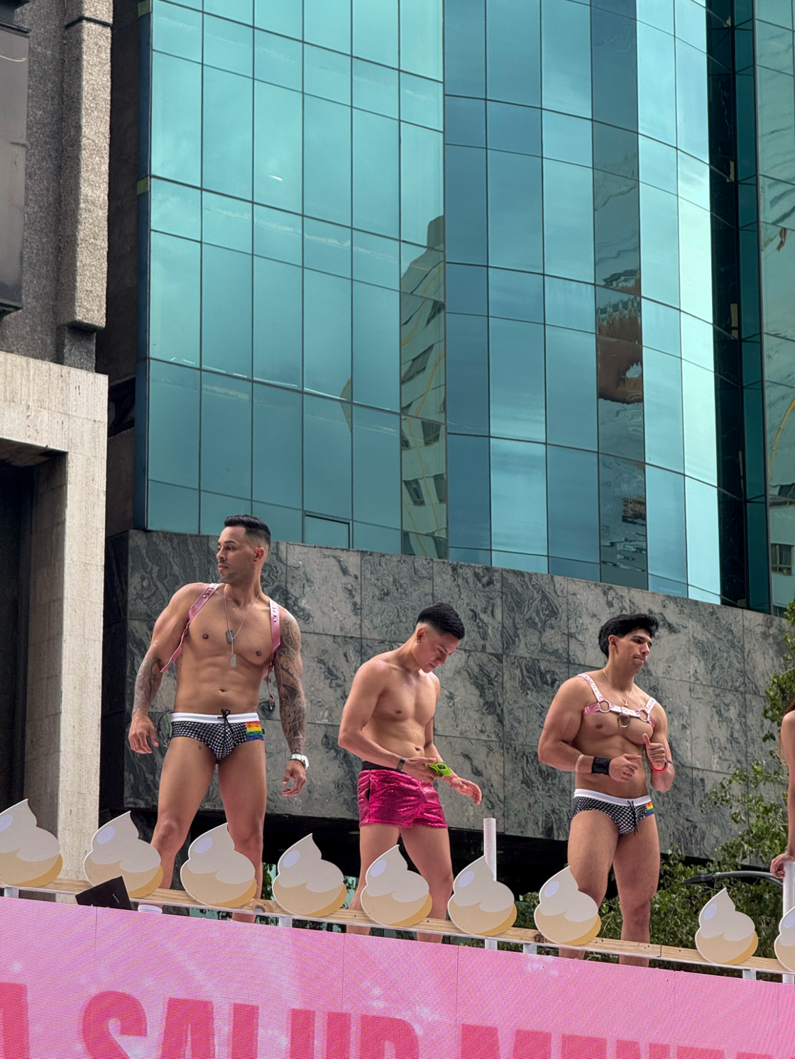 Three men dance in speedos on top of a float at Mexico City Pride.