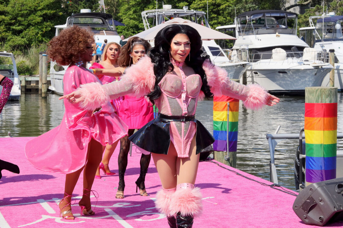 Drag queen Alyssa Hunter walks down a pink carpeted pier at Fire Island Pines in a pink dress.