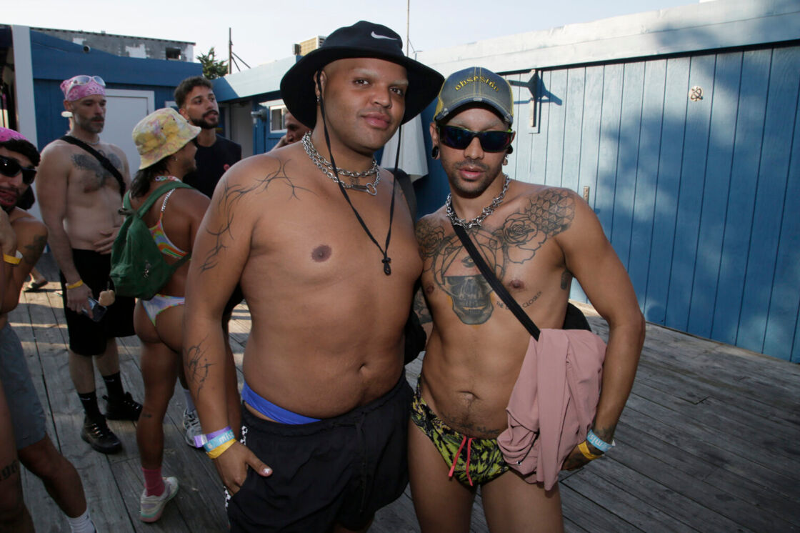 Kandy Muse and Dahlia Sin, pictured out of drag, pose in swimsuits and hats on the deck at Fire Island Pines.