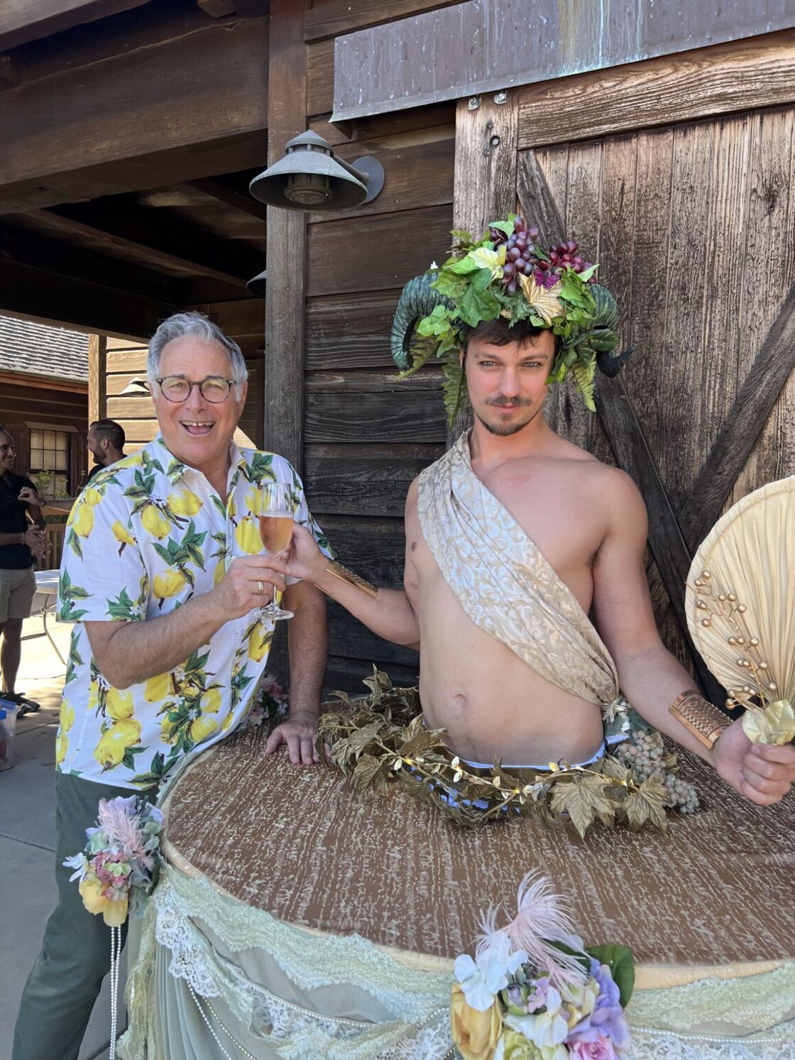 A man toasts a shirtless man dressed like Dionysus at Gay Wine Weekend.