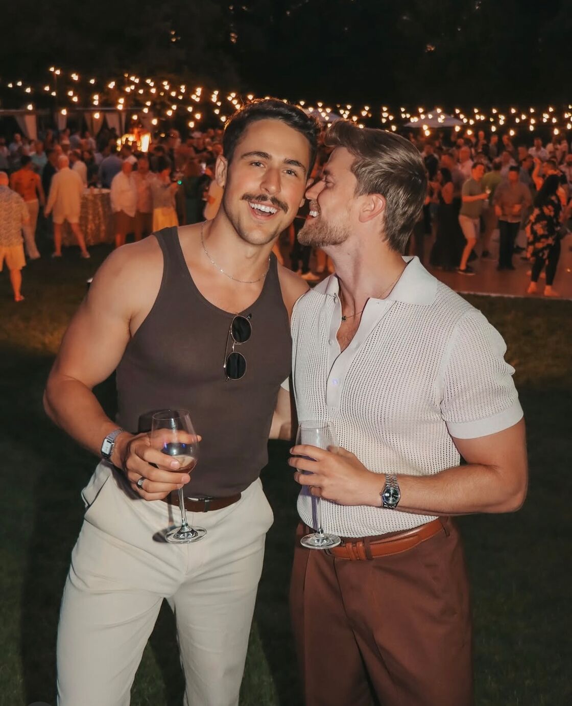 Two men smile and hold up their wine at an outdoor event at Gay Wine Weekend.