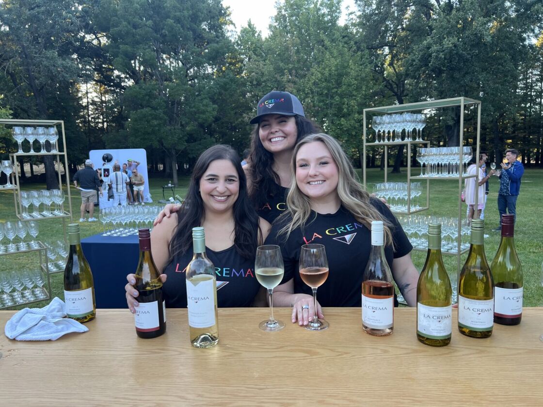 La Crema Winery sits with their booth at Gay Wine Weekend.