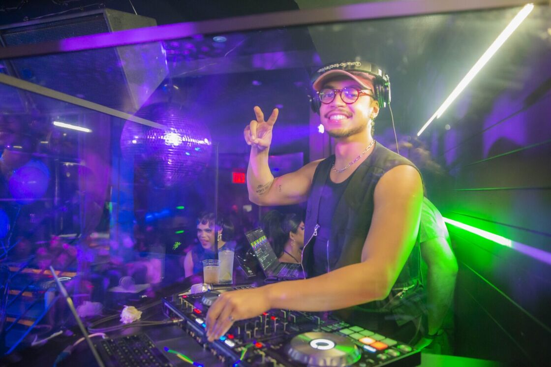 DJ Alpha Moses poses in a tanktop at the DJ booth at The Ritz Bar & Lounge.