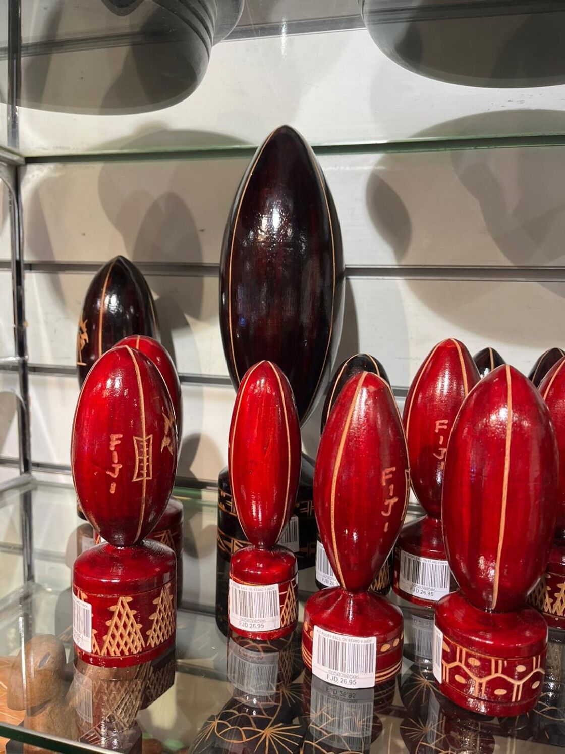 A close-up of red rugby statuettes on a Fiji gift shop shelf reading "Fiji."