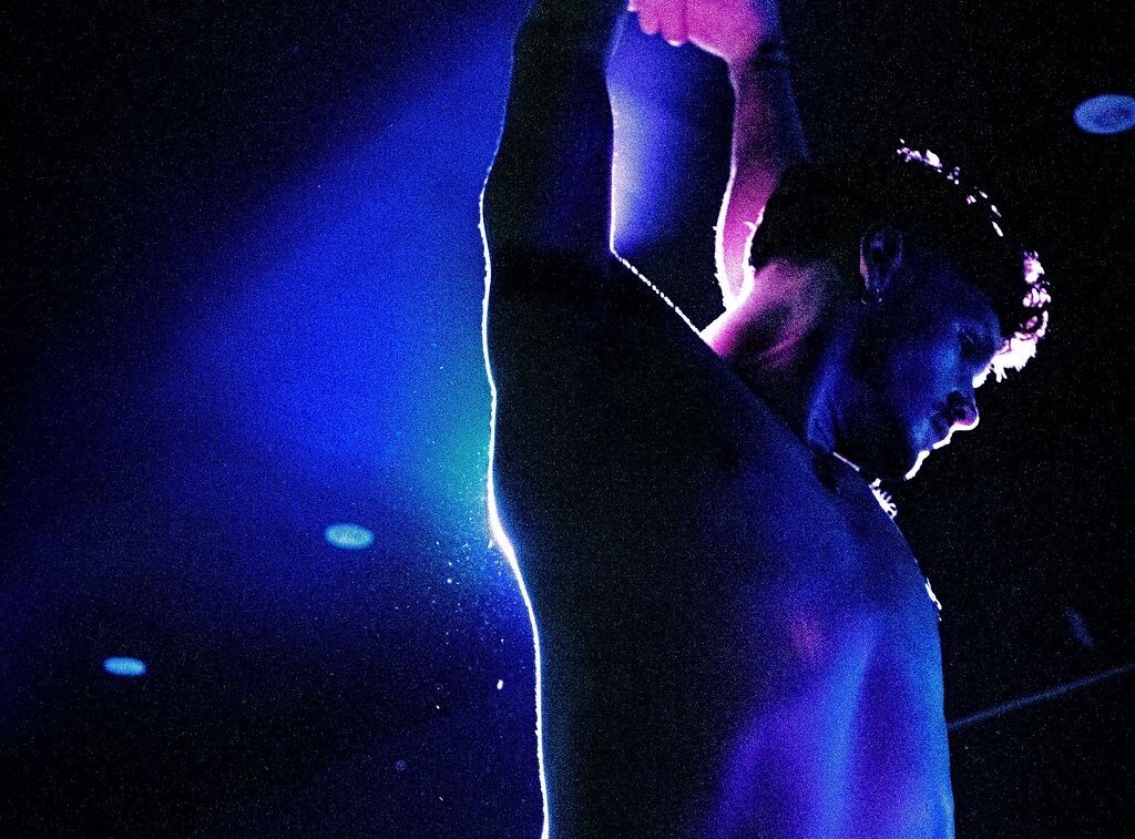 A shirtless dancer poses in purple lighting at The Ritz Bar & Lounge.