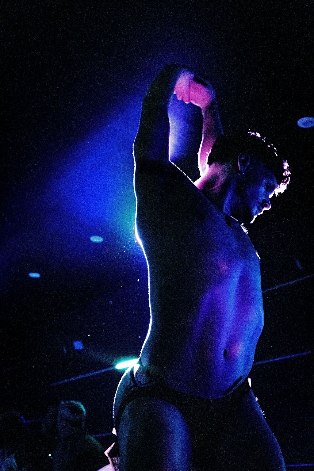 A shirtless go-go dancer poses in purple lighting at The Ritz Bar & Lounge.