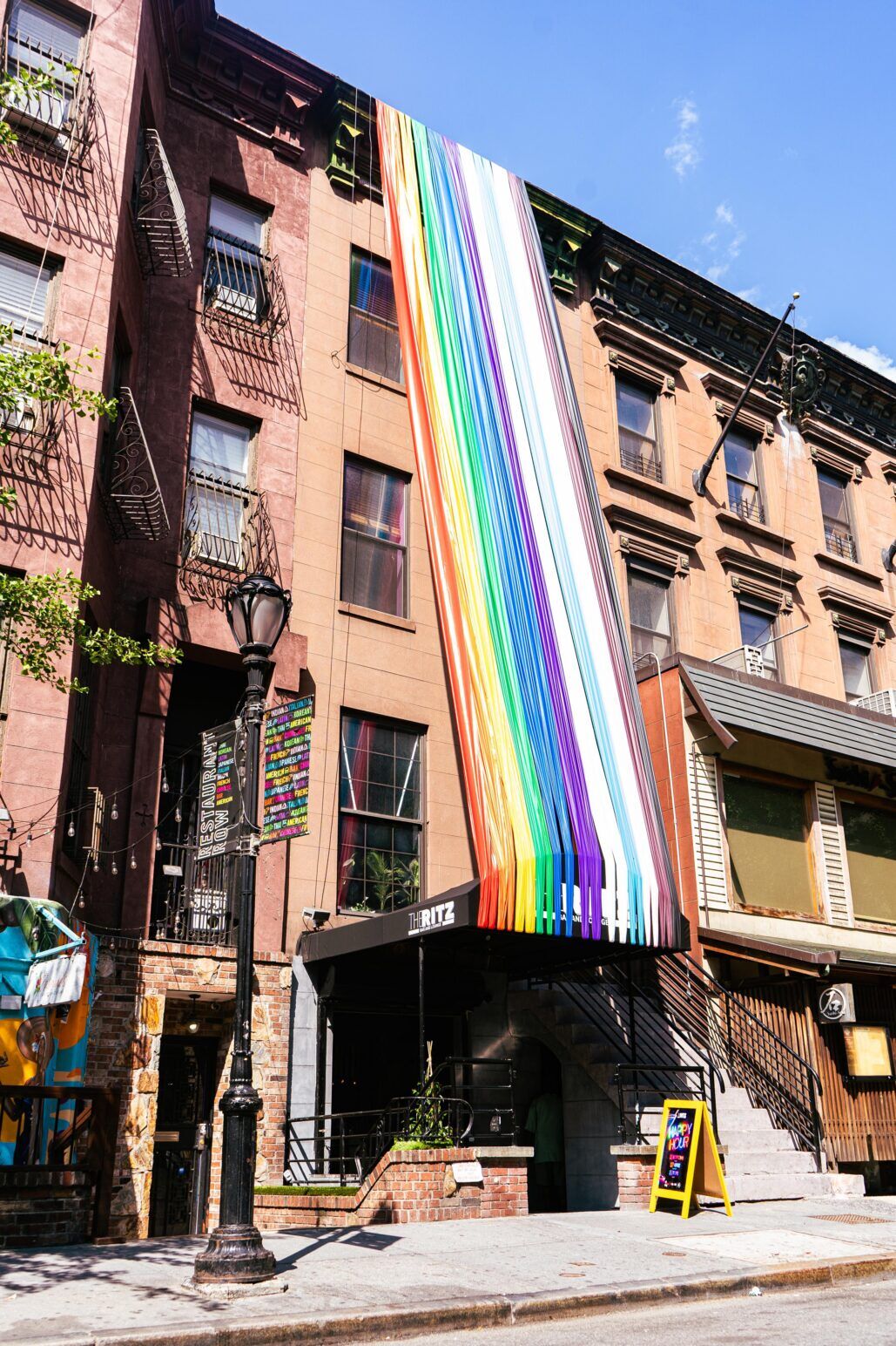 The Ritz Bar & Lounge pictured during Pride month with giant rainbow streamers hanging from its awning to the rooftops.