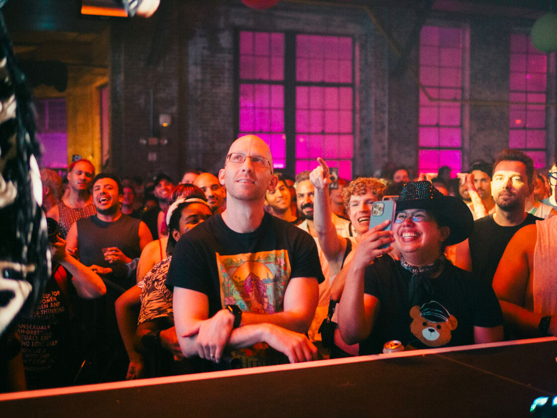A group of attendees smile and cheer while watching drag performers at Bushwig.