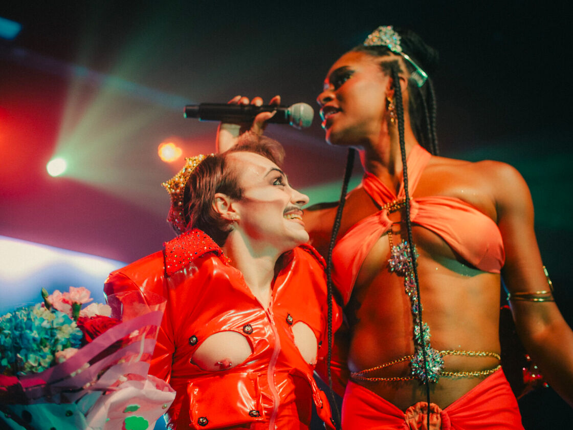 A drag queen and drag king pose on stage smiling after winning titles at Bushwig.