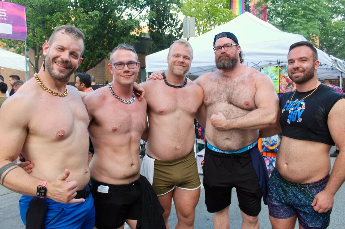 A group of muscular shirtless men smile and flex at Chicago's Market Days.