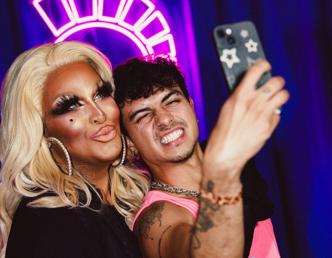 Roxxxy Andrew smiles in drag while a fan takes a selfie of them both at Bushwig.