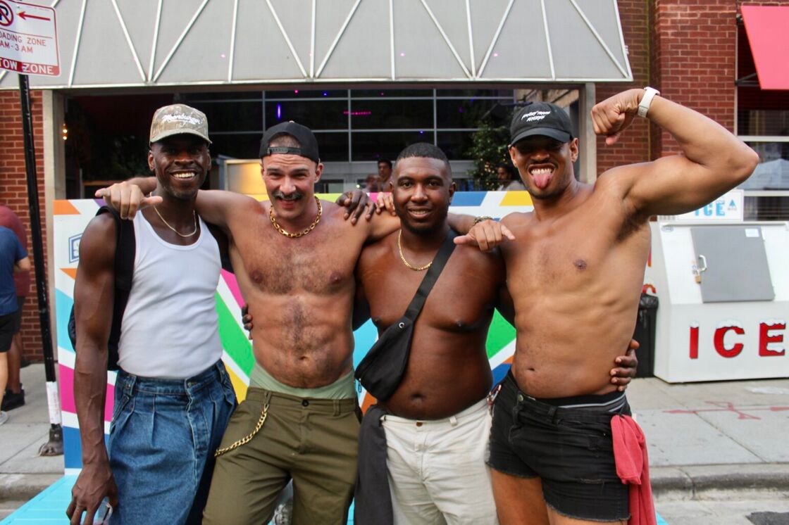 A group of men pose shirtless and flexing on the streets of Chicago's Market Days.