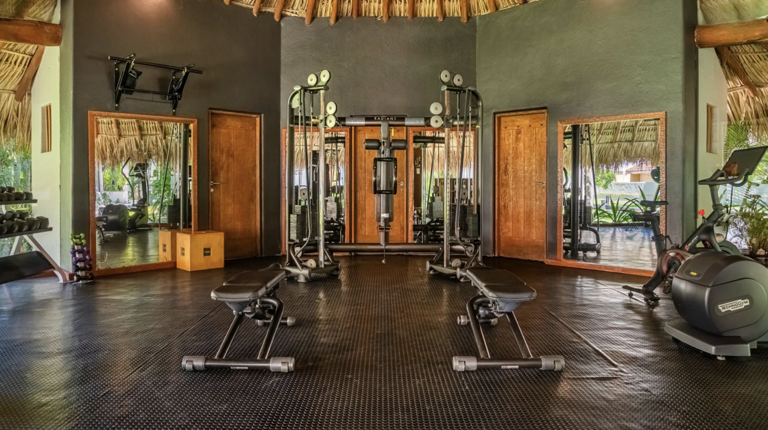 The fitness center at Thompson Zihuatanejo, with windows peeking out at tropical scenery.