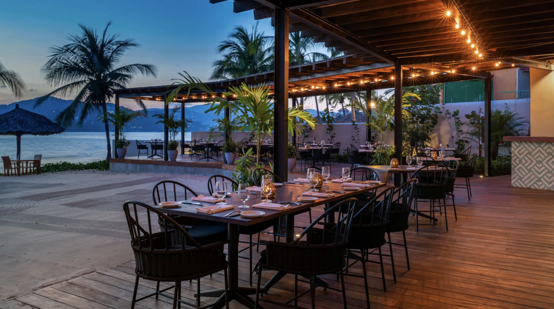 A waterside restaurant is set for dinnertime under a roof of twinkling lights at Thompson Zihuatanejo.