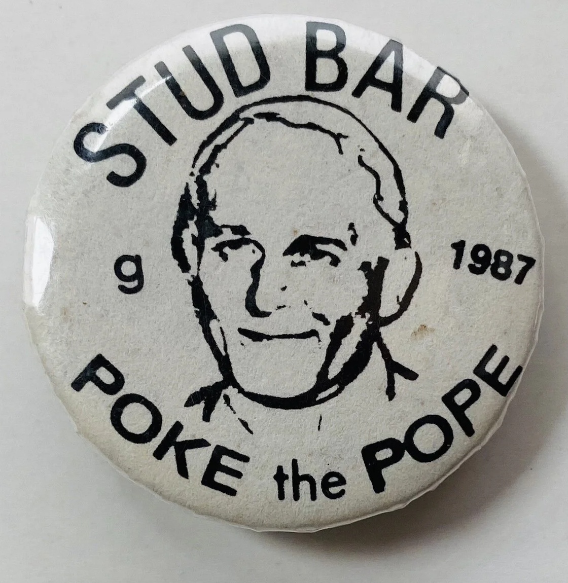 A button for The Stud reading "Poke the Pope" from 1987.