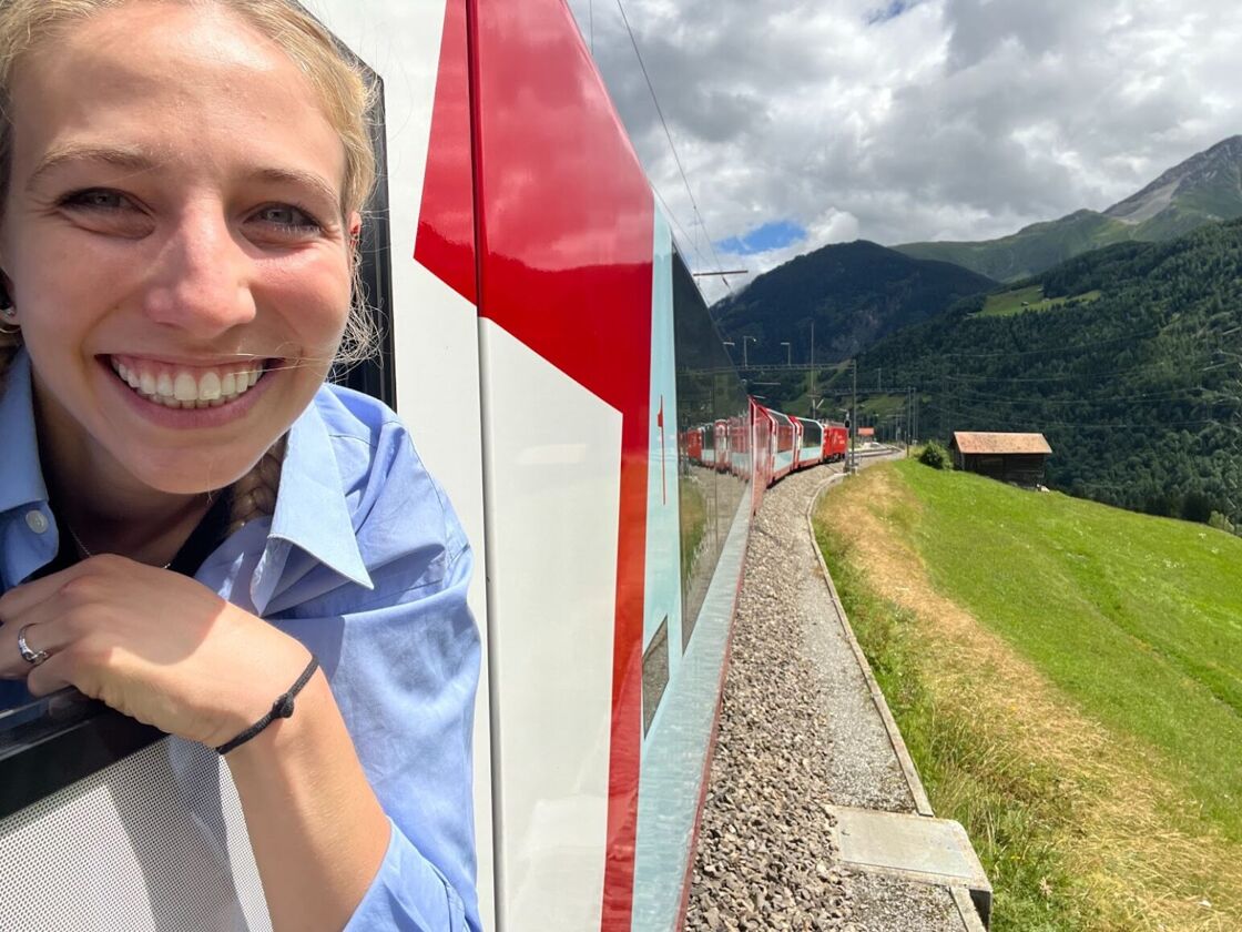 Alexia Garcia smiles while peeking her head out of the window of Switzerland's Glacier Express.