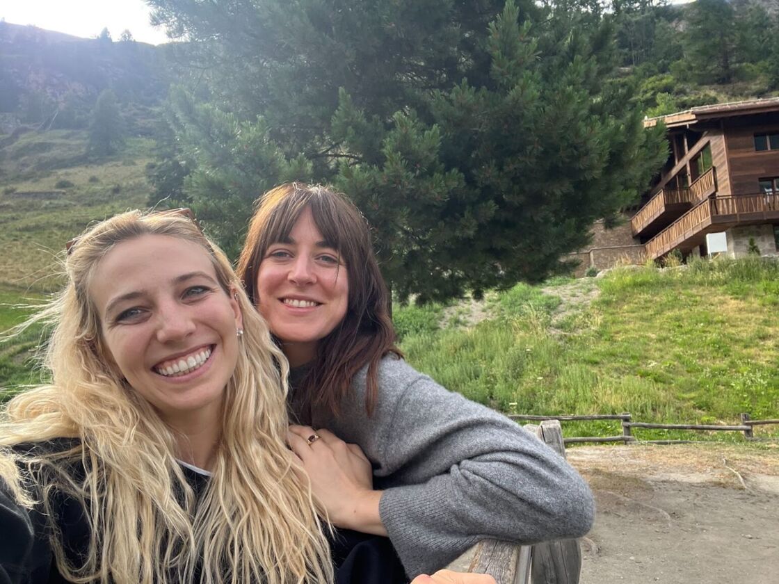 Alexia Garcia and her girlfriend smile in front of a scenic and green Switzerland hilltop.