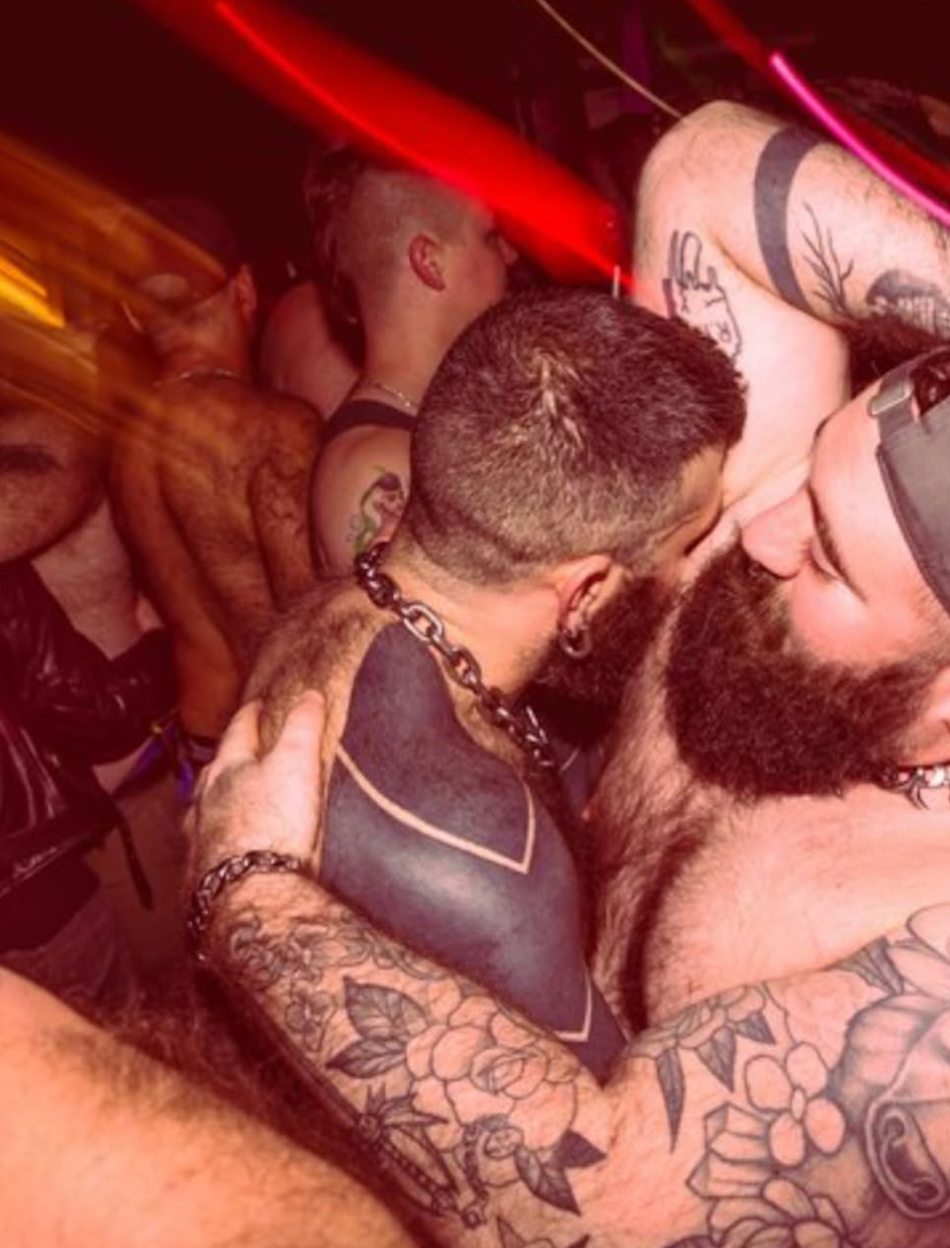 Two shirtless men embrace at a dance night for The Stud.