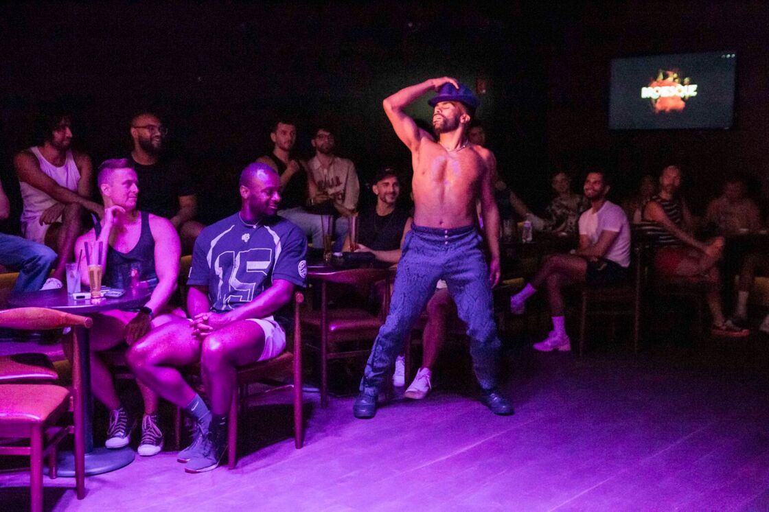 A shirtless man dances on audience members in a top hat at Brolesque.