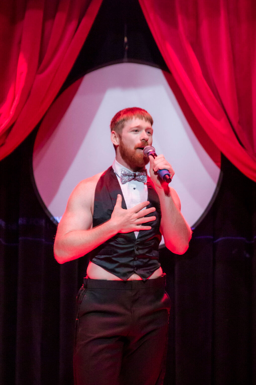 A red-haired man performs wearing a tightly-fit suit top at Boylesque.