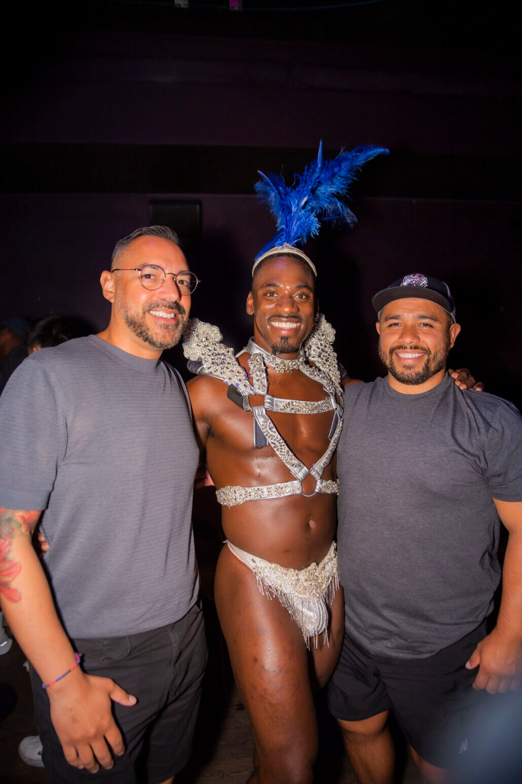 Audience members pose with a Boylesque dancer in a beaded halter top and brief at Balcon Salon. 