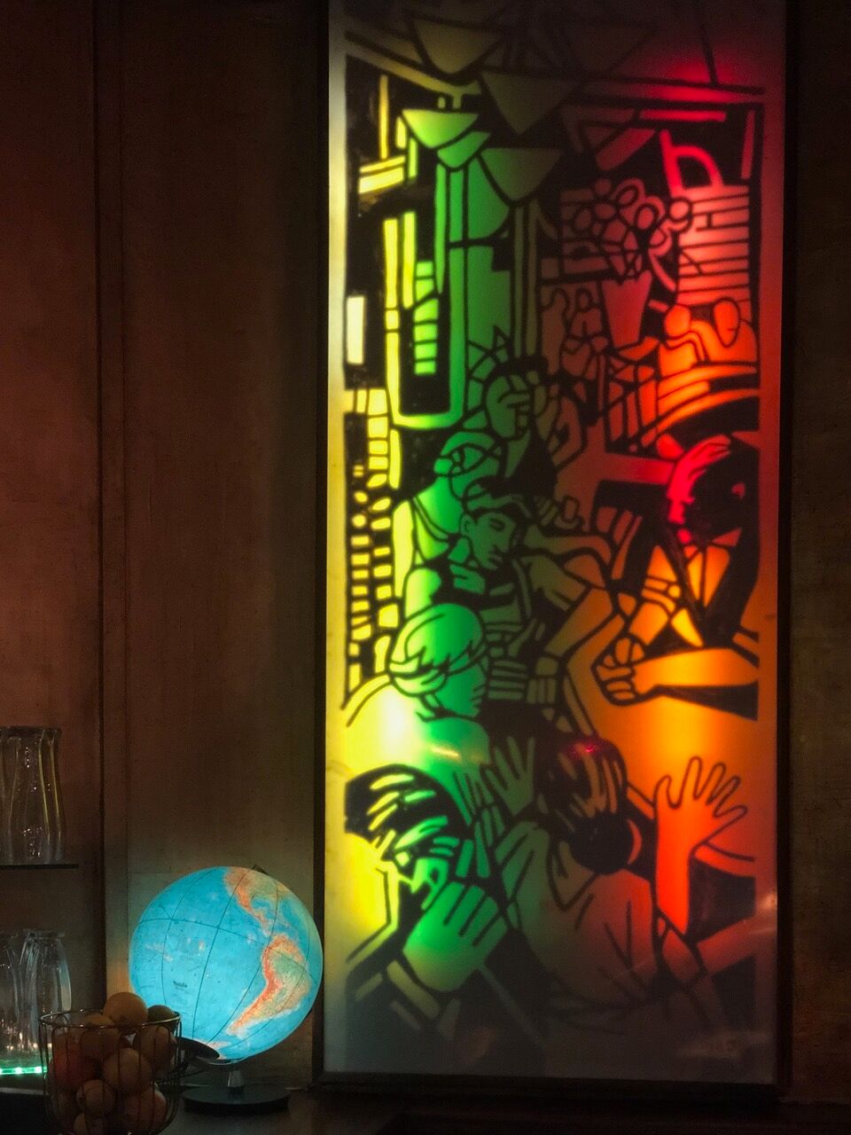 A stained glass and rainbow-colored illustrated pane of men fraternizing at a bar at Hafen in Berlin.