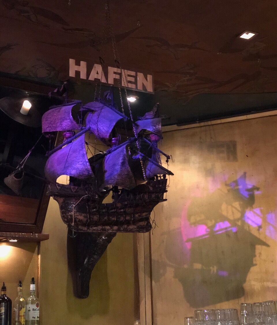 A pirate ship hands from the ceiling in front of the logo for Hafen in Berlin.