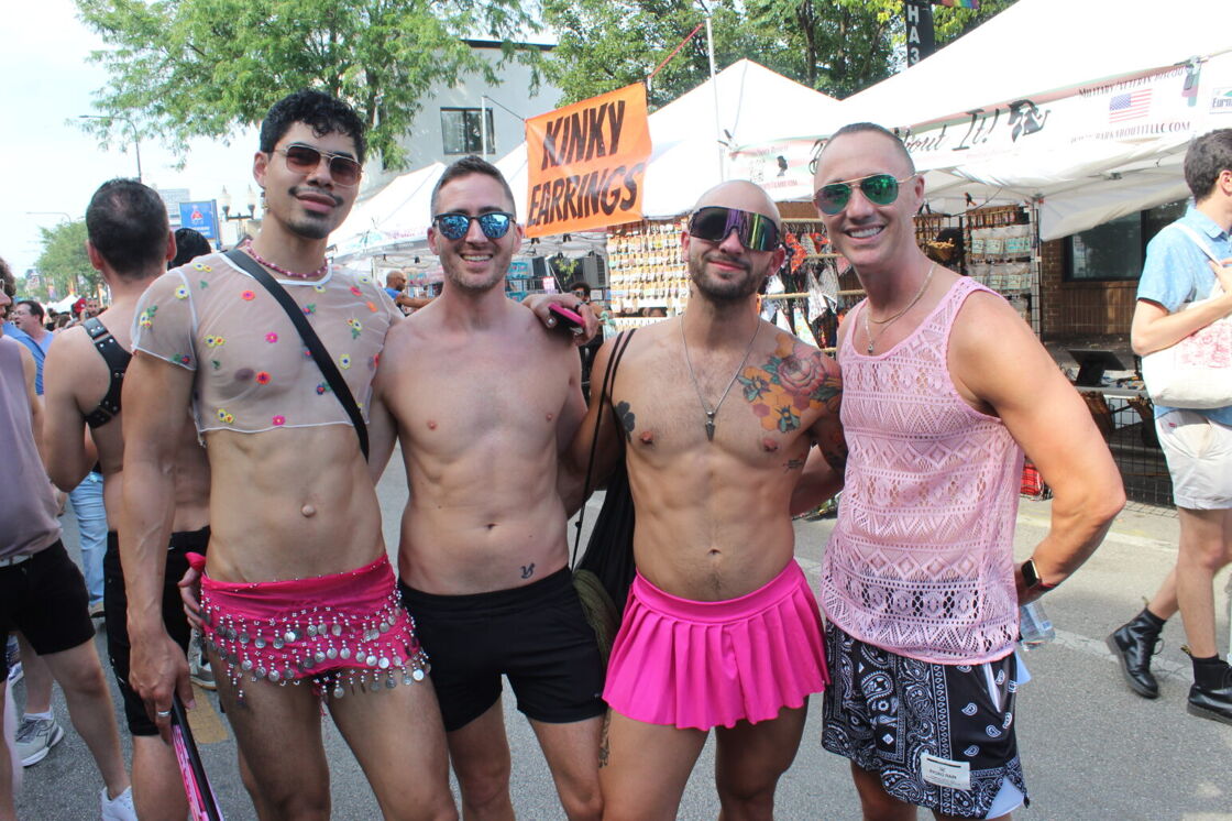A group of shirtless men pose in various pink skirts and tank tops at Chicago's Market Days.