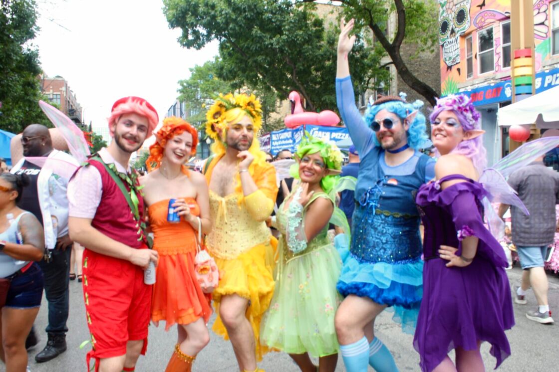 A group of Market Days attendees pose in different colors of the rainbow, dressed as fairies.