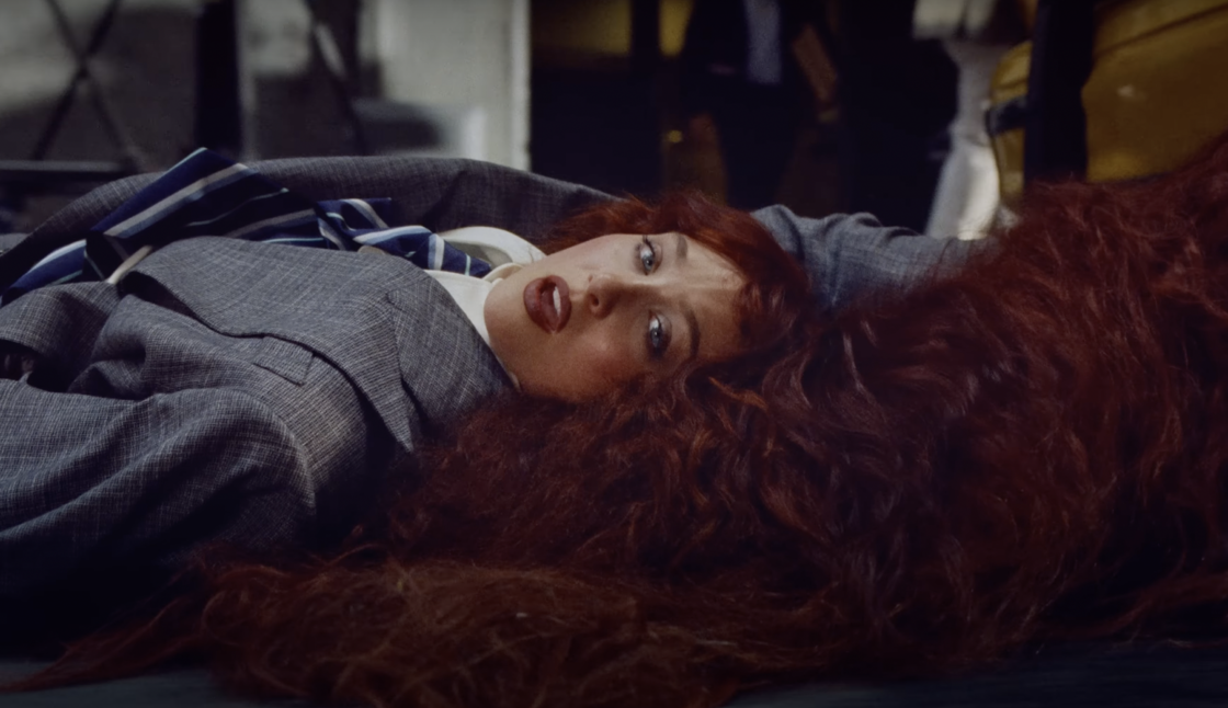 Chappell Roan sings in an oversized suit while being dragged by her hair stuck in a taxi door in the music video for "The Subway."